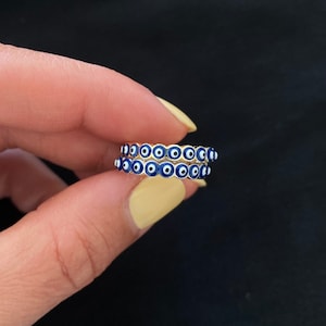 May include: Gold ring with multiple blue and white evil eye charms.