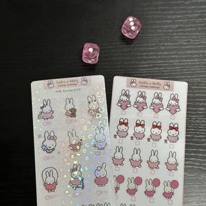 Puede incluir: Dos hojas de pegatinas holográficas con el personaje Miffy. La hoja de la izquierda tiene un desafío de ahorro con un objetivo de $ 150. La hoja de la derecha tiene un desafío de ahorro con un objetivo de $ 150. Ambas hojas presentan una variedad de ilustraciones de Miffy.