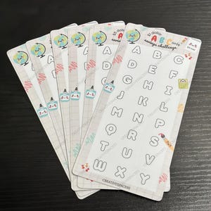 May include: A set of 7 colorful alphabet stickers with a globe, paintbrush, and glue bottle design. The stickers are labeled "$1 dollar ABC note savings challenge".