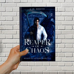 May include: A book cover for "Reaper of Chaos" by C.D. Britt. The cover features a dark-haired figure split down the middle, one side a skeleton in a black cloak, the other a man in a white shirt. The title is in large, stylized white letters.