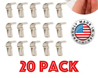 May include: A pack of 20 silver-colored plastic hooks, designed for hanging items from a ceiling. The hooks are shaped like a 'J' and have a small lip on the top to help secure them in place. The hooks are made in the USA and are labeled as a 20 pack.