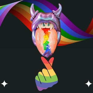 Puede incluir: Una lengua de diablo púrpura e iridiscente con rayas arcoíris y colmillos. La lengua está sobre un fondo arcoíris con un gesto de mano arcoíris en primer plano.