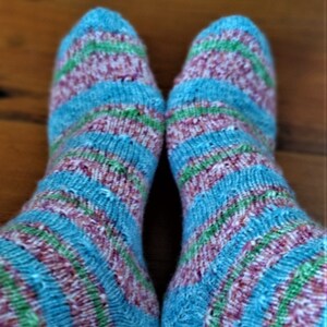 May include: A pair of blue, pink, and green striped socks. The socks are knitted and have a textured look.