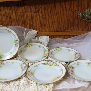 May include: Set of six vintage floral patterned porcelain soup bowls with gold trim. The bowls are white with pink and green floral designs.