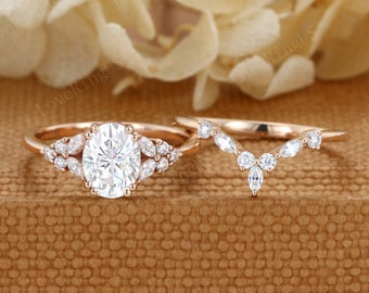 May include: A rose gold engagement ring set with an oval-shaped center stone and a matching marquise-shaped wedding band. Both rings feature a delicate floral design with small round stones.