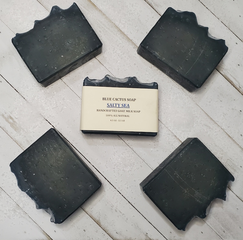 Peut inclure: Cinq savons carr&eacute;s gris fonc&eacute; avec un bord textur&eacute; unique sont dispos&eacute;s sur une surface claire &agrave; grain de bois. Le savon central est &eacute;tiquet&eacute; "Blue Cactus Soap Salty Sea", savon artisanal au lait de ch&egrave;vre.