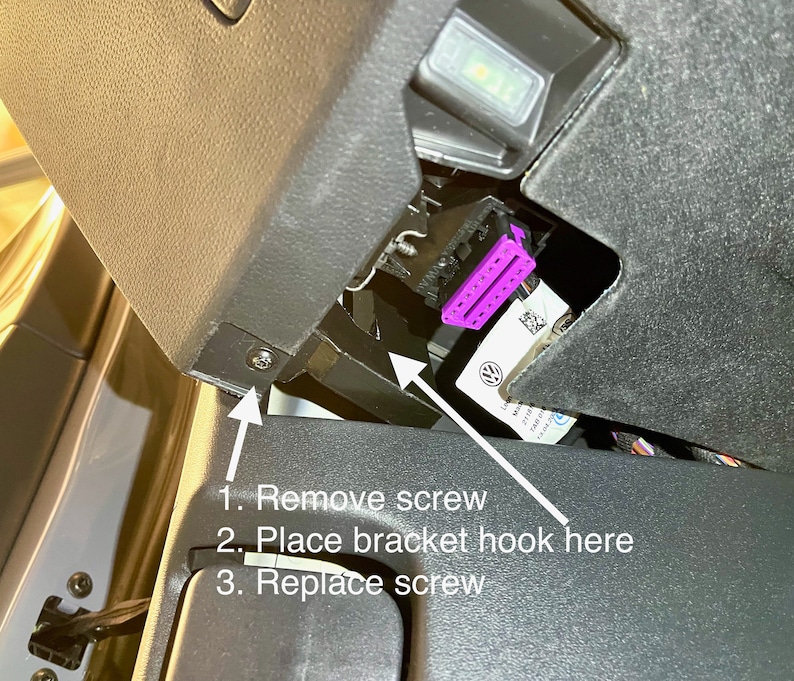 May include: A close-up of a black plastic panel with a screw and a purple connector. The text on the panel reads: "1. Remove screw 2. Place bracket hook here 3. Replace screw".
