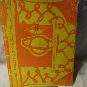May include: A vintage book with a yellow and orange cover featuring abstract illustrations. The cover design includes looping lines, a ruler-like element, and other geometric shapes. The book's spine is visible, showing the edge of the pages.
