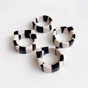 Anillo grueso de arcilla polimérica negra y blanquecina con diseño a cuadros y sutiles detalles dorados, tallas 7–8.5