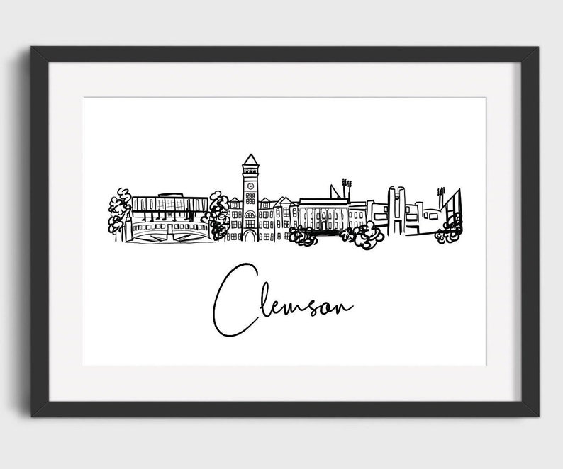 May include: Black framed print featuring a minimalist line drawing of the Clemson, South Carolina skyline. The word "Clemson" is written in cursive below the skyline. The artwork is in black and white.