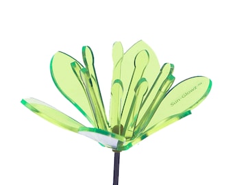 Könnte beinhalten: Eine grüne Acryl-Blume mit einem schwarzen Stiel. Die Blume hat mehrere Schichten Blütenblätter und ist mit "Sun-Glowz TM" gekennzeichnet.