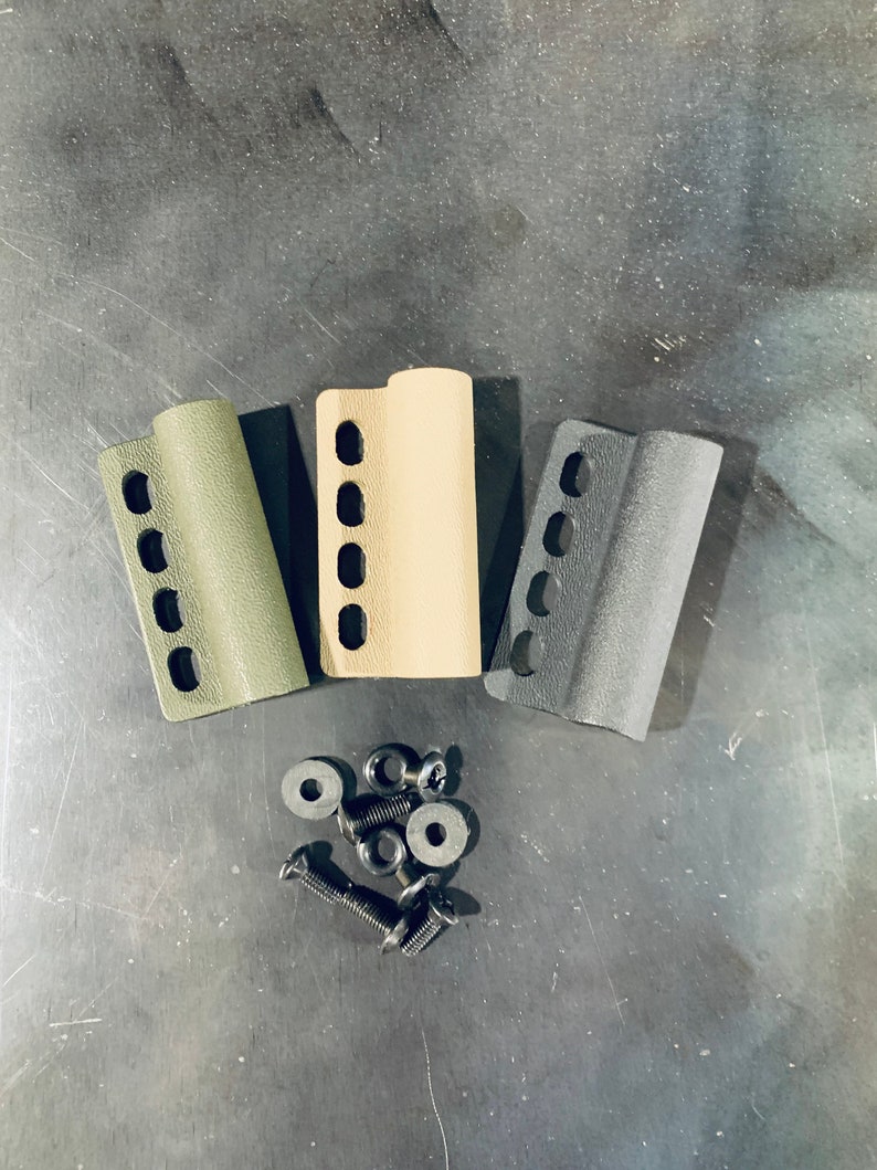 May include: Three plastic grip panels in green, beige, and black with a series of holes. The panels are arranged in a semi-circle with a pile of black screws and washers in the centre.