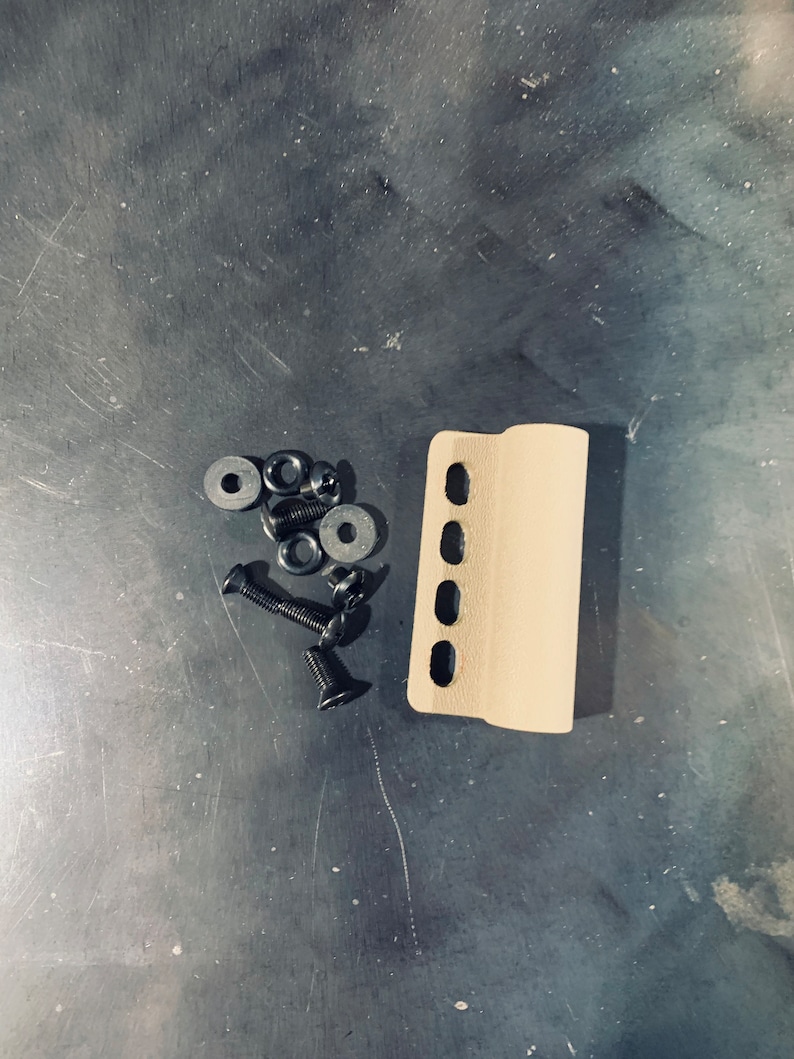 May include: A beige plastic handguard with six holes and a rounded edge. The handguard is accompanied by five black screws and five black washers.