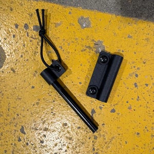 May include: A black ferro rod with a black handle and a black sheath. The ferro rod is a survival tool used to create sparks for starting fires. The sheath has two screws to attach it to a belt or other gear.