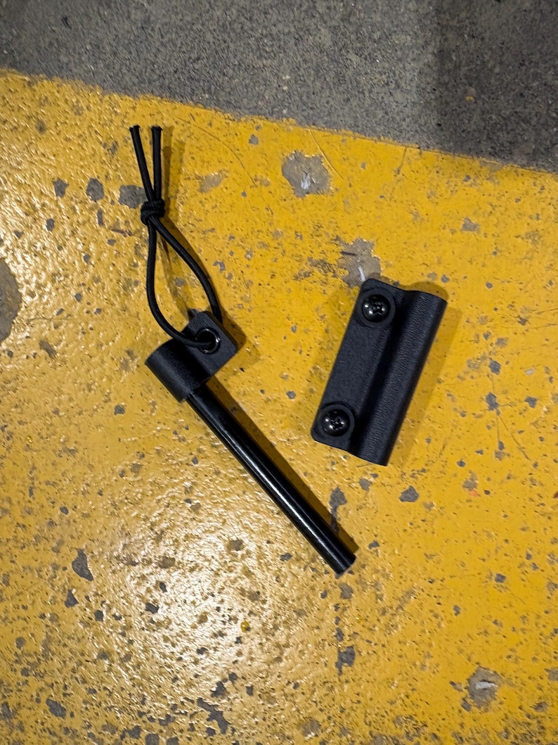 May include: A black ferro rod with a black handle and a black sheath. The ferro rod is a survival tool used to create sparks for starting fires. The sheath has two screws to attach it to a belt or other gear.