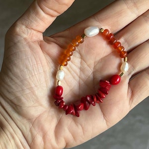 May include: A red coral and orange agate beaded bracelet with gold spacers and white pearls.