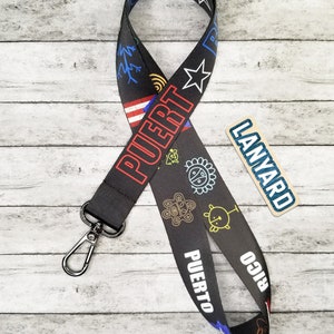 May include: Black lanyard with a white "PUERTO RICO" text and colorful designs. The lanyard has a silver clip and a small tan tag that says "LANYARD".
