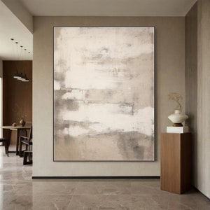May include: Abstract painting with a beige and white color scheme. The painting is hanging on a wall in a modern home.