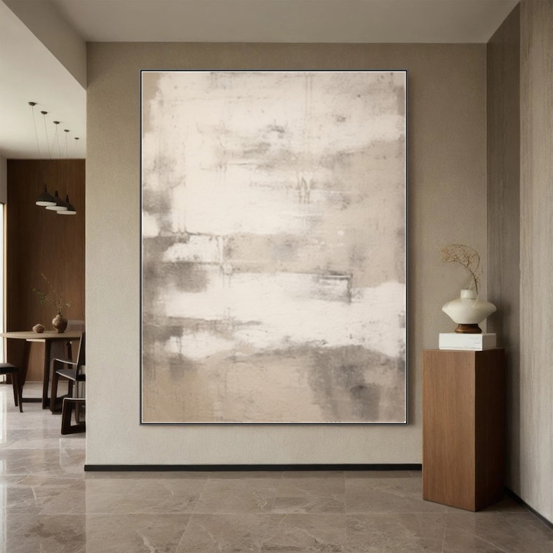 May include: Abstract painting with a beige and white color scheme. The painting is hanging on a wall in a modern home.
