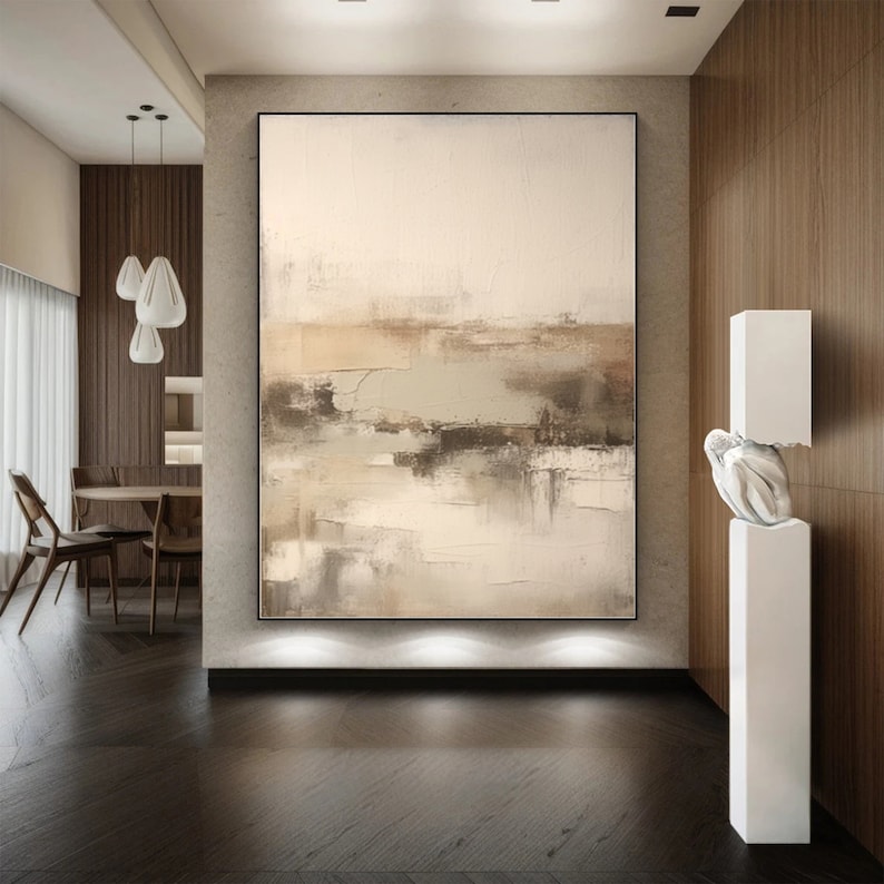May include: Abstract painting in shades of beige, brown, and gray with a textured finish. The painting is hanging on a wall in a modern interior with wood paneling.