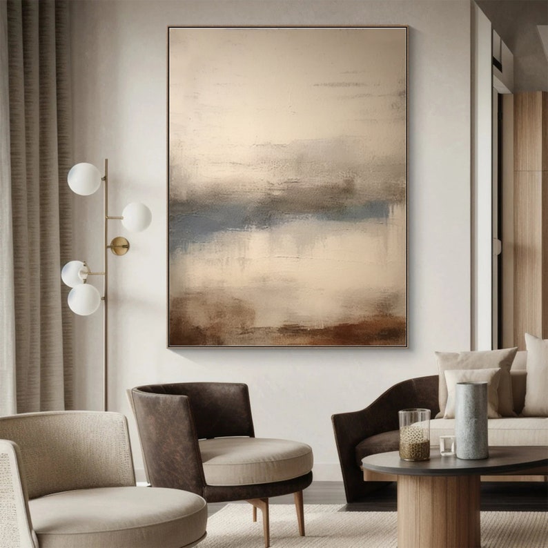 May include: Abstract painting with brown, beige, and blue hues. The painting features horizontal brushstrokes and a layered effect, creating a sense of depth and movement. The painting is framed and displayed on a wall in a modern living room.