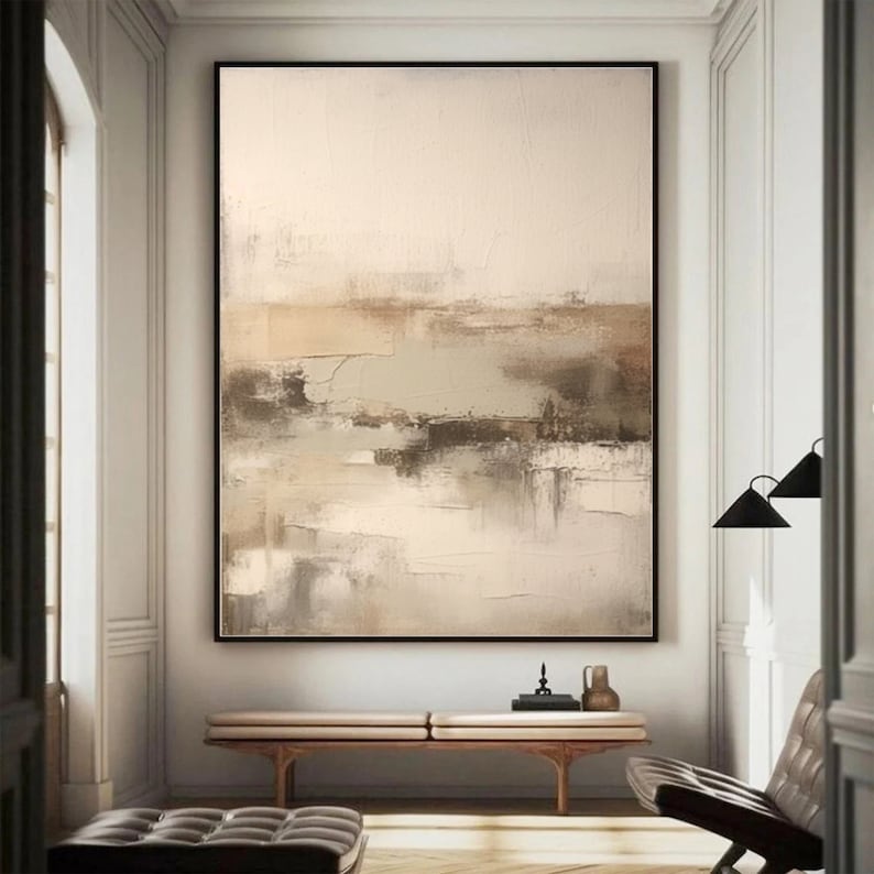 May include: Abstract painting with a beige background and brown, gray, and green brushstrokes. The painting is framed and hanging on a white wall.
