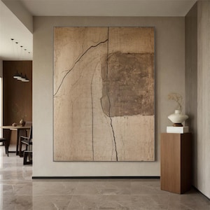 May include: Large abstract canvas art with a neutral color palette. The artwork features a beige background with a large brown square and black linear accents. The piece is displayed in a modern interior setting.