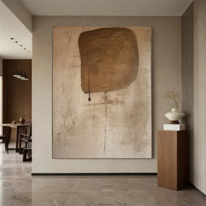 May include: Abstract painting with a large brown shape on a beige background. The shape is slightly off-center and has a rough texture. The background is textured and has a subtle pattern.