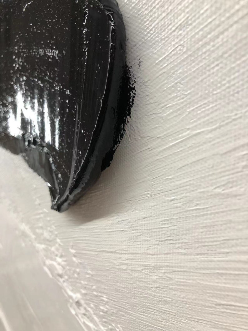 May include: Close-up of a black abstract painting on a white textured canvas.