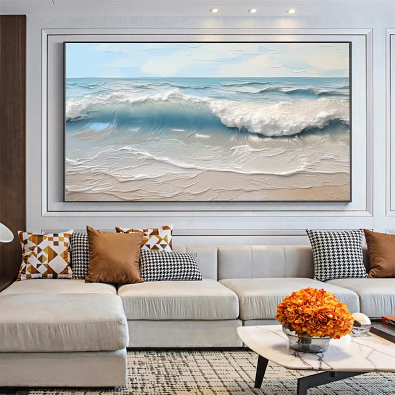 May include: Large framed artwork depicting a seascape with a textured, three-dimensional effect. The painting features a dynamic ocean scene with crashing waves in shades of blue and white, and a sandy beach.