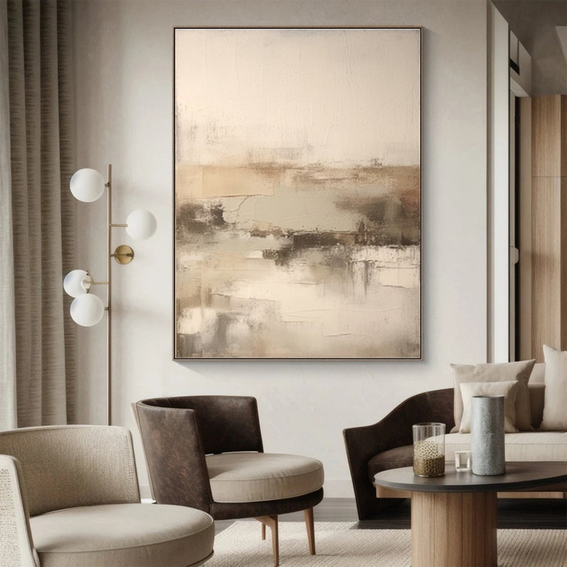 May include: Abstract painting with brown, beige, and green hues. The painting is framed and hanging on a white wall in a living room setting.