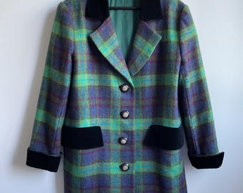 Op de afbeelding: Een vintage geruite blazer in groen, paars en blauw. De blazer heeft een zwarte fluwelen kraag, zakafwerking en manchetten. Het heeft vier decoratieve knopen en een groene voering. Een klassiek kledingstuk.