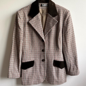 May include: A blazer featuring a multi-colored houndstooth pattern in red, green, and white. The garment includes a dark brown velvet collar and matching pocket flaps, three front buttons, and a Gianni Versace label at the neckline.