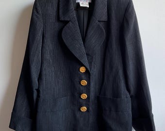May include: Black blazer with gold-colored buttons. The blazer has a textured pattern and a classic design. The blazer has a notched lapel and two front pockets. The buttons are round and ornate. The blazer is a vintage piece.