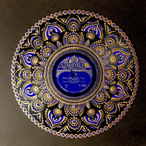 Könnte beinhalten: Eine schwarze Schallplatte, die mit einem goldenen und blauen Mandala-Design bemalt ist. Das Plattenlabel ist für "Masks and Faces - Tango" von Geraldo's Los Cauchos Tango Orchestra. Das Plattenlabel stammt von Decca Records, The Supreme Record, Made in England.