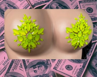 May include: A mannequin torso with lime green leaf-shaped embellishments over the breasts, set against a backdrop of pink-tinted hundred-dollar bills. The image has a pop art aesthetic.