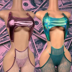May include: Two metallic bodysuits, one pink and one teal, displayed on mannequins. The tops have a unique cut-out design, and the bottoms feature lace detailing. The background is a pink dollar bill pattern.