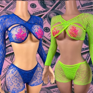 May include: Two sets of long-sleeved lace lingerie on mannequins. One set is royal blue, the other is neon green. Both feature a cropped, crisscross-front top with floral-patterned lace and matching high-cut lace shorts with a sheer texture.