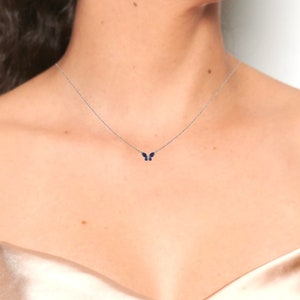 May include: A delicate silver chain necklace with a small blue butterfly pendant.