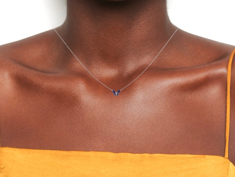 May include: A silver chain necklace with a small blue butterfly pendant.