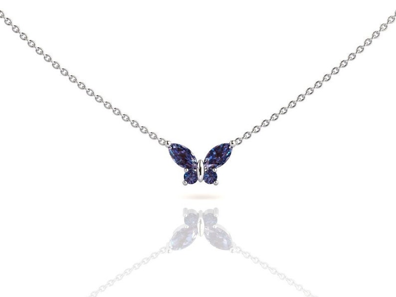 May include: A silver chain necklace with a blue butterfly pendant. The butterfly is made of faceted gemstones.