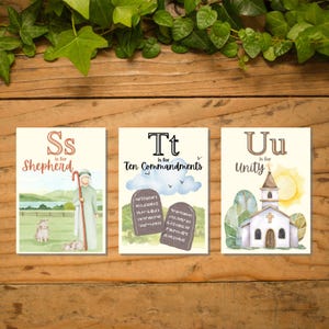 May include: Three illustrated cards with religious themes. The first card features a shepherd with a staff and sheep, labeled "S is for Shepherd." The second card shows the Ten Commandments, labeled "T is for Ten Commandments." The third card depicts a church, labeled "U is for Unity."
