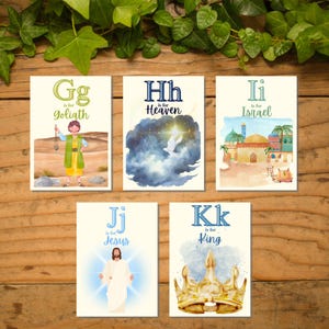 May include: A collection of five illustrated cards with religious themes. The cards feature the letters G, H, I, J, and K, each paired with a word: Goliath, Heaven, Israel, Jesus, and King. The illustrations include a biblical scene, a dove, and a golden crown.