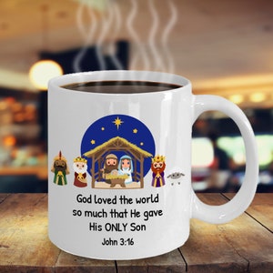 Peut inclure: Une tasse à café en céramique blanche avec une scène de la nativité de Noël et le texte "Dieu a tellement aimé le monde qu'il a donné son Fils unique Jean 3:16".