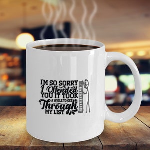 May include: White ceramic coffee mug with a black graphic that says "I'm so sorry I offended you it took a while to get through my list". A stick figure is holding a ruler.