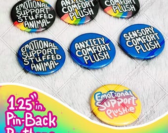 May include: A collection of pin-back buttons with various phrases, including "Emotional Support Stuffed Animal," "Anxiety Comfort Plush," and "Sensory Comfort Plush." The buttons are 1.25 inches in diameter and feature colorful designs.