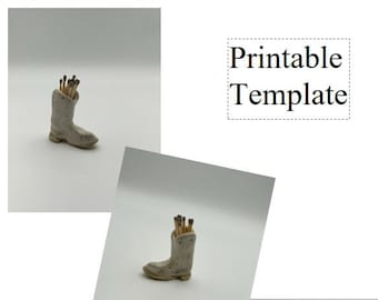 May include: A white ceramic boot with a speckled finish, used as a matchstick holder. The boot is filled with wooden matchsticks. The image includes the text "Printable Template" and "Dirty Gal Pottery".