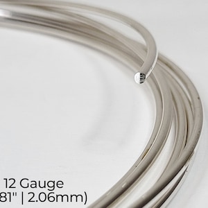 Pode incluir: Close-up de uma bobina de fio de prata, calibre 12, com 2,06 mm de di&acirc;metro. O fio &eacute; brilhante e liso.