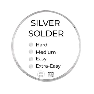 May include: A circular coil of silver solder wire with a white label featuring the text SILVER SOLDER, Hard, Medium, Easy, Extra-Easy, WIZ ART, and MADE IN THE USA. The wire is metallic silver in color and arranged in a continuous circular loop.
