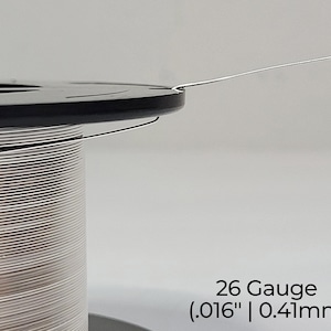 Pode incluir: Um carretel de fio prateado de calibre 26, com um di&acirc;metro de 0,41 mm.